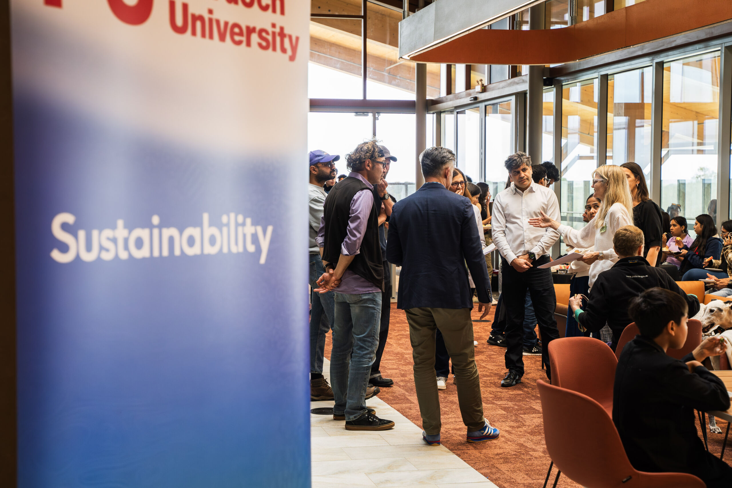 Banner in the foreground reads 'Murdoch University Sustainability' with people networking in the background.